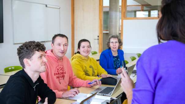 vier masterstudenten luisteren aandachtig naar een docent voor ze