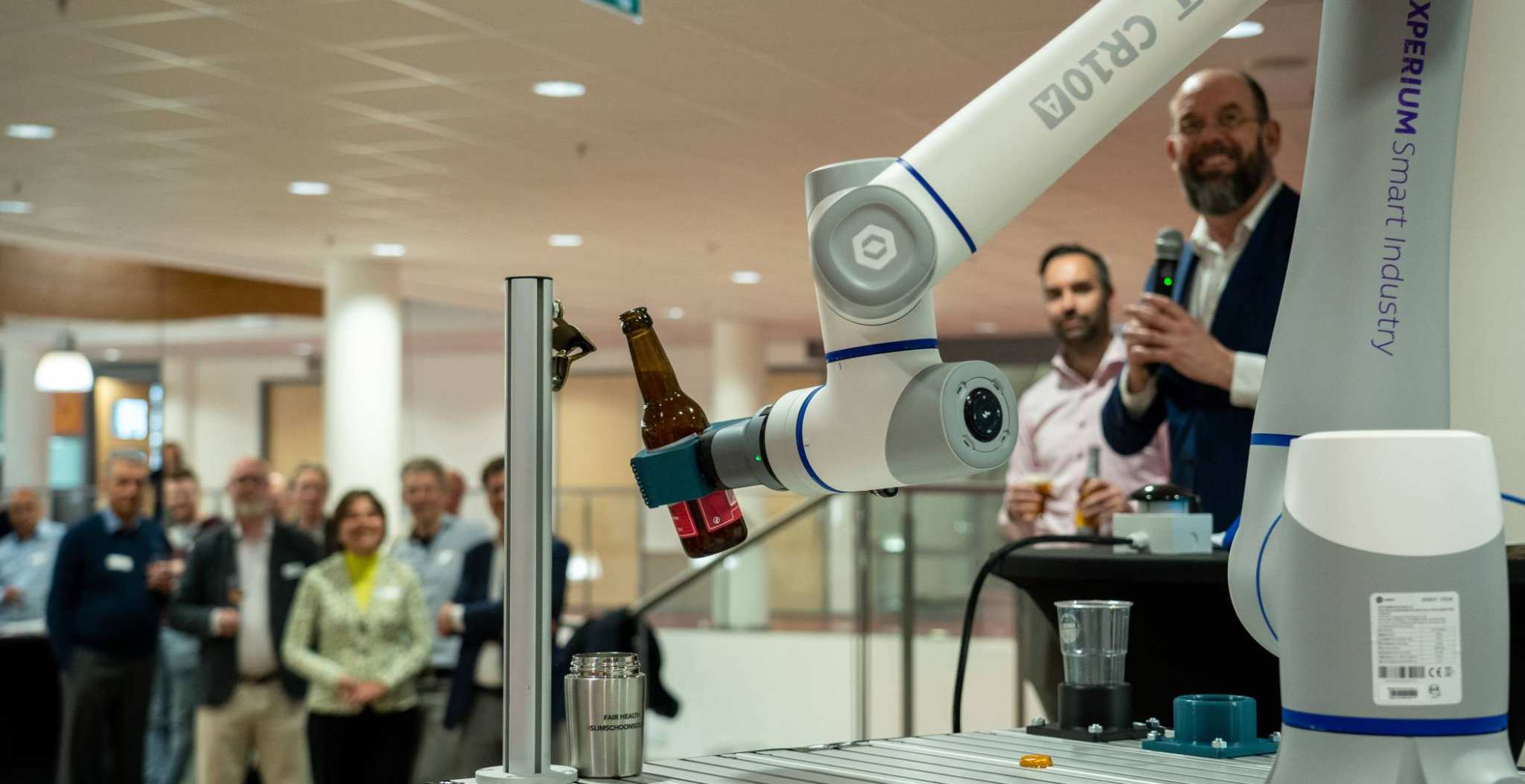 Het iXperium is geopend op 16 april. Een cobot pakt het door AI samengestelde biertje en schenkt een glas in.