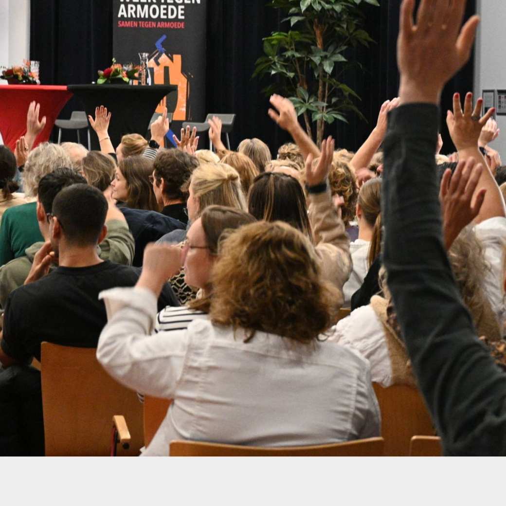 publiek met handen omhoog tijdens symposium beyond borders week tegen armoede