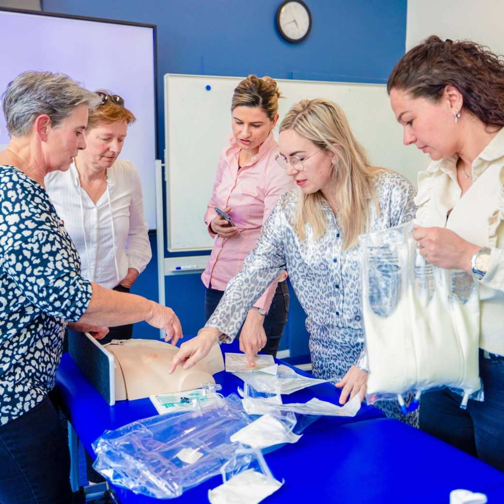 Docent geeft praktijkles aan vier vrouwen
