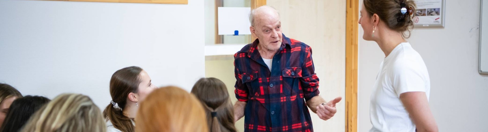 taalambassadeur Michel spreekt met bezoekers van de workshop Beperkte basisvaardigheden en structurele geldzorgen. Hij heeft een kaal hoofd en draagt een rood en zwart geruit blouse.