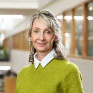 Portretfoto Nanda Olde, witte blouse dragend met daarover groene trui