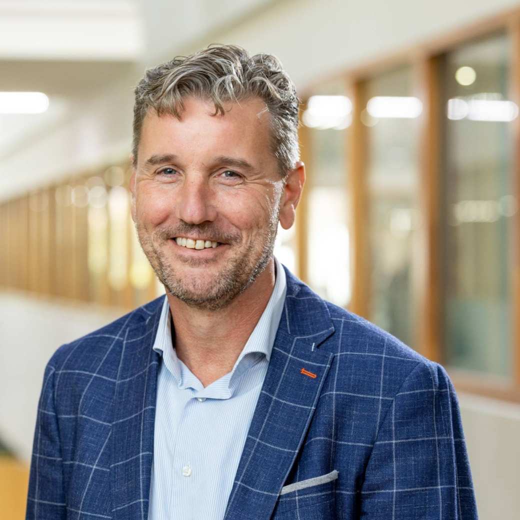 Portretfoto Fred de Jong, blauwe blouse en gemeleerd blauw jasje dragend