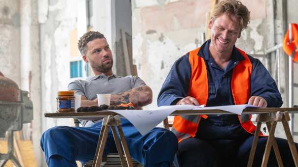 Omscholer naar techniek kijkt gelukkig naar zijn bouwtekening, met een collega ernaast.