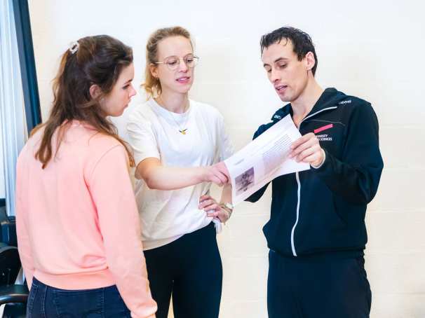 Docent helpt studenten en legt wat uit met behulp van een blaadje.