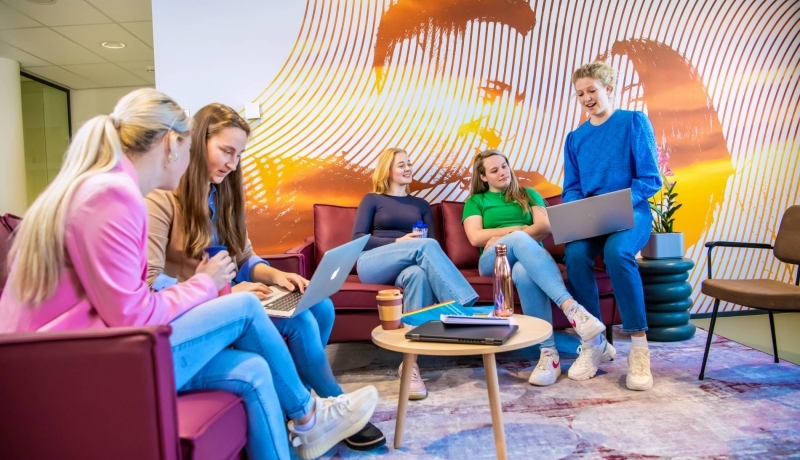 Groep studenten met laptops op een bank