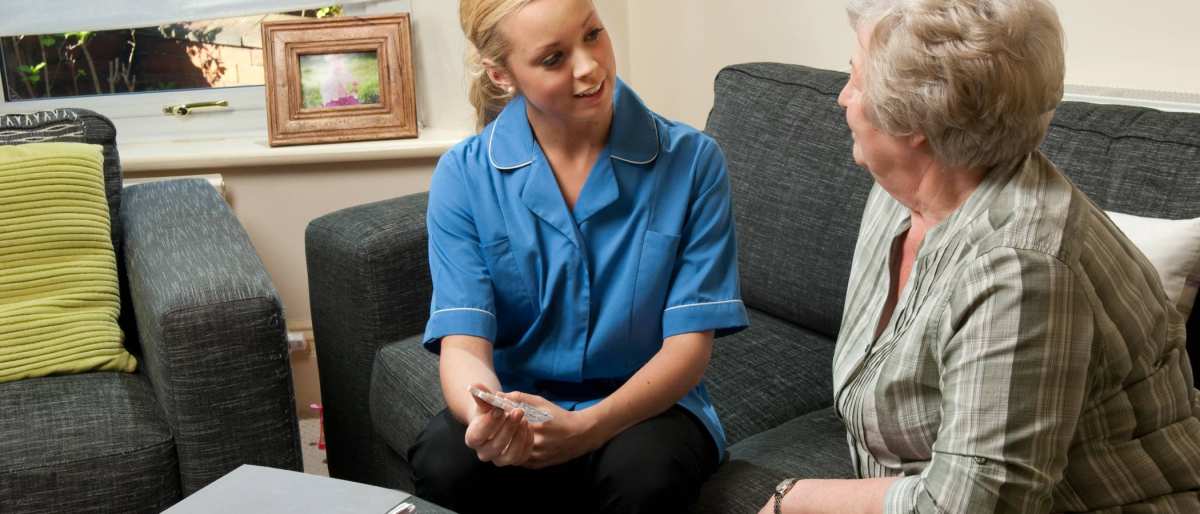 Verpleegkundigen in uniform op bank met oudere dame (istock)
