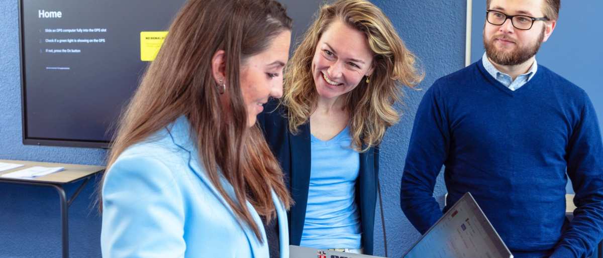 Vrouw is in gesprek met docent. Vrouw heeft lichtblauw jasje aan. Opleiding maag-, lever-, darmverpleegkundige