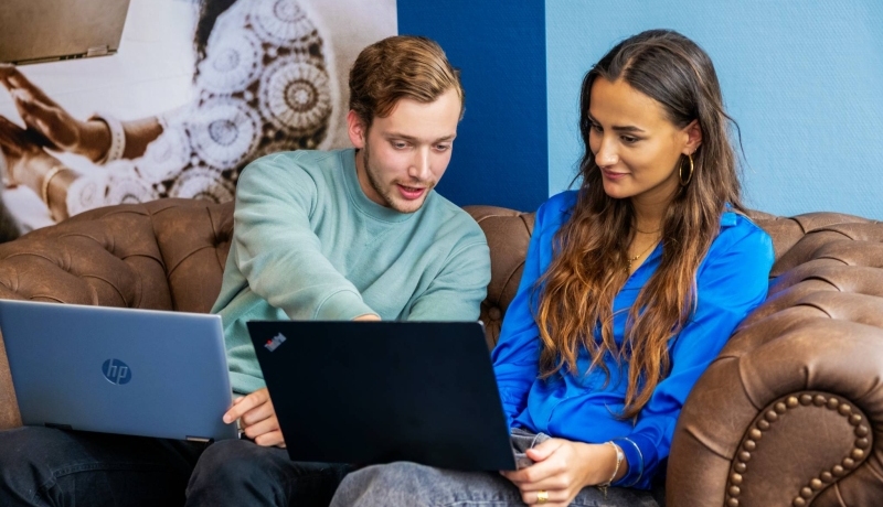 Commerciële Economie 2 studenten op bank met laptop