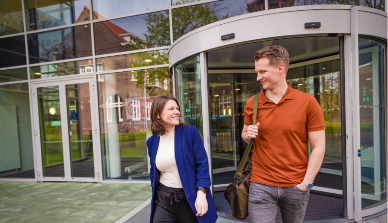 werknemer en arbeidsdeskundige lopen een gebouw uit