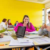 Twee studenten hbo Nederlands bladeren door een boek in de mediatheek.