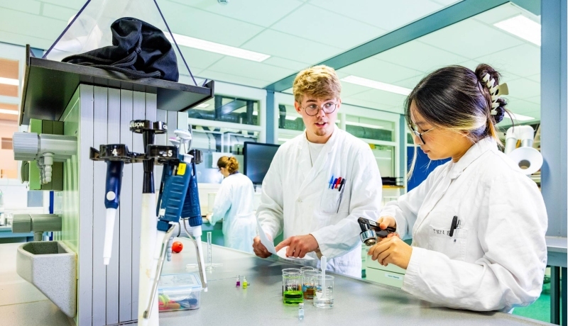 2 voltijdstudenten van de mastertrack Chemistry overleggen met elkaar in het laboratorium.