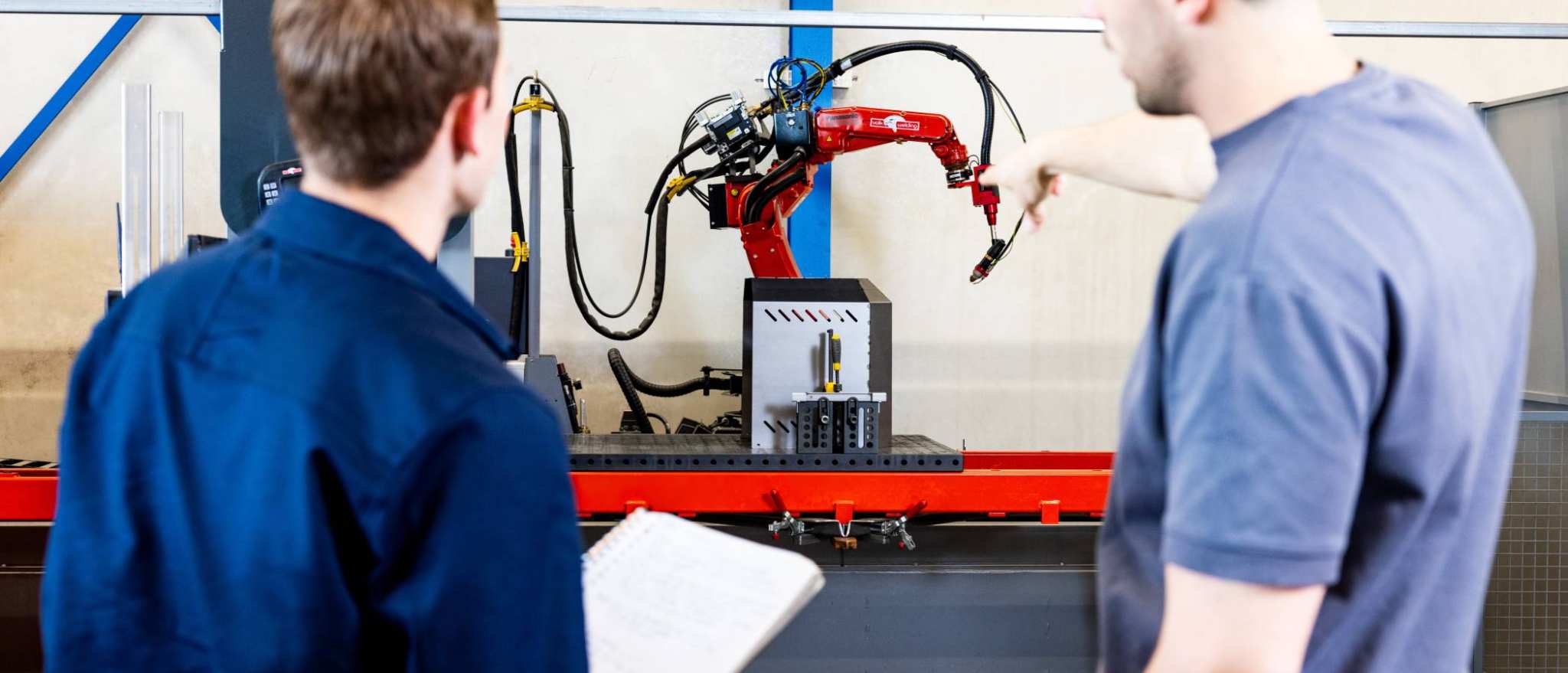 Technische Bedrijfskunde studenten Jort en Derk samen bij robot arm.