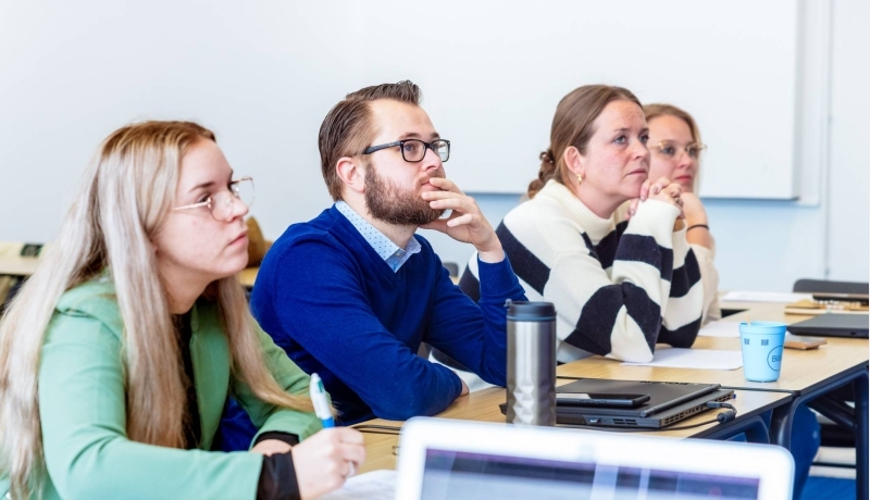 4 studenten Ad POH luisteren naar een docent in de les.