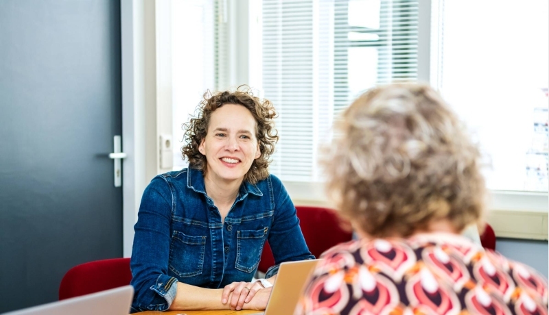 2 docenten zitten aan tafel in overleg