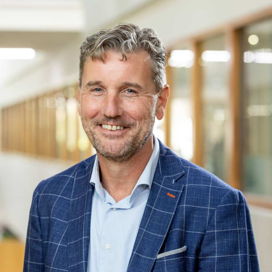 Portretfoto Fred de Jong, blauwe blouse en gemeleerd blauw jasje dragend