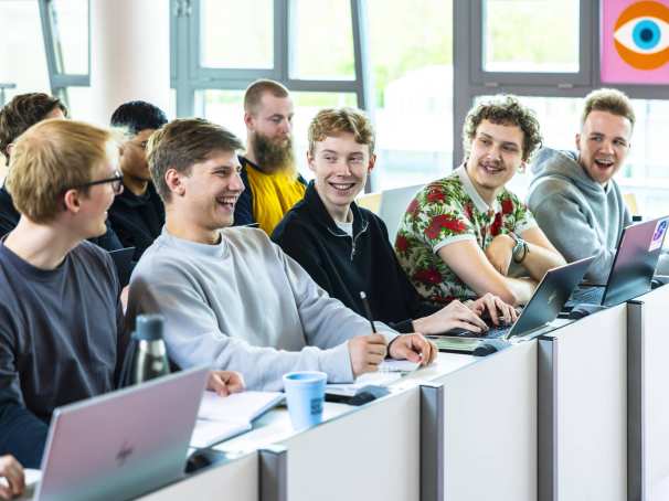 hbo ict studenten zitten lachend in de collegezaal te luisteren naar een docent