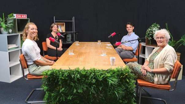 Deelnemers podcast zitten om een tafel