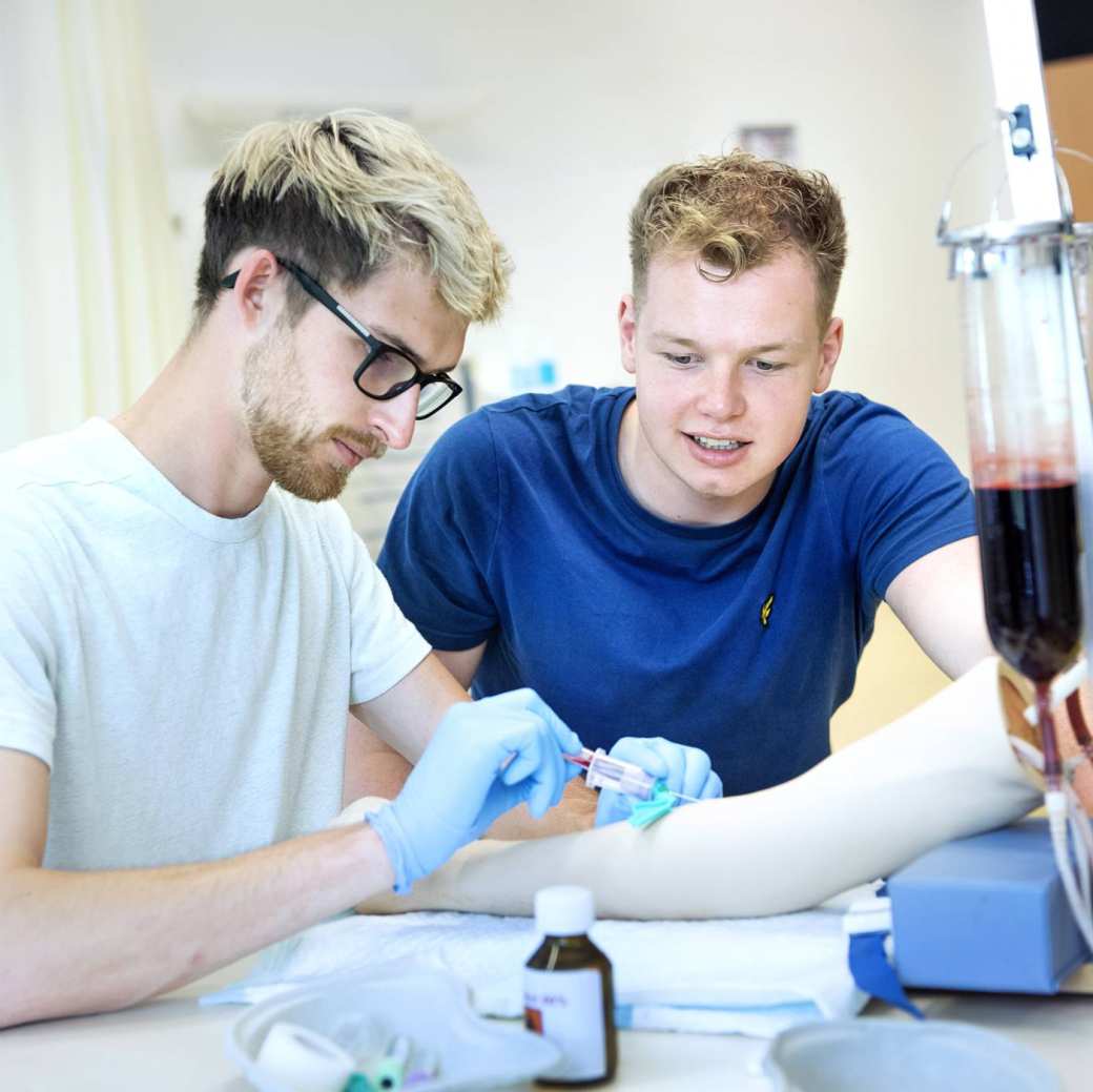 Twee studenten Medische Hulpverlening oefenen met bloedprikken