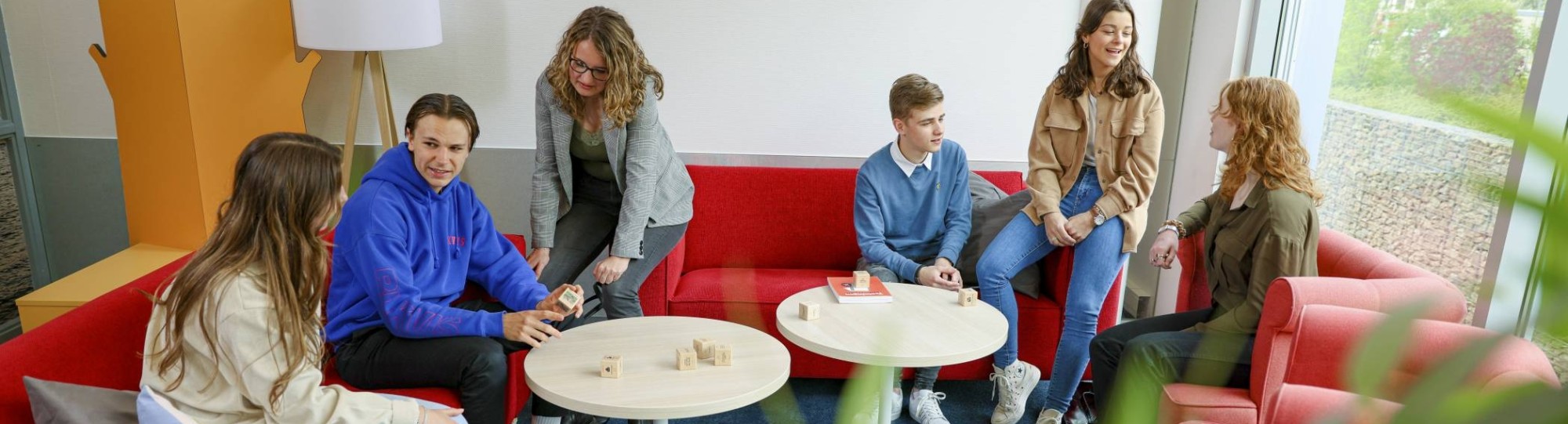 Meerdere studenten van de opleiding toegepaste psychologie aan het praten op een rode bank