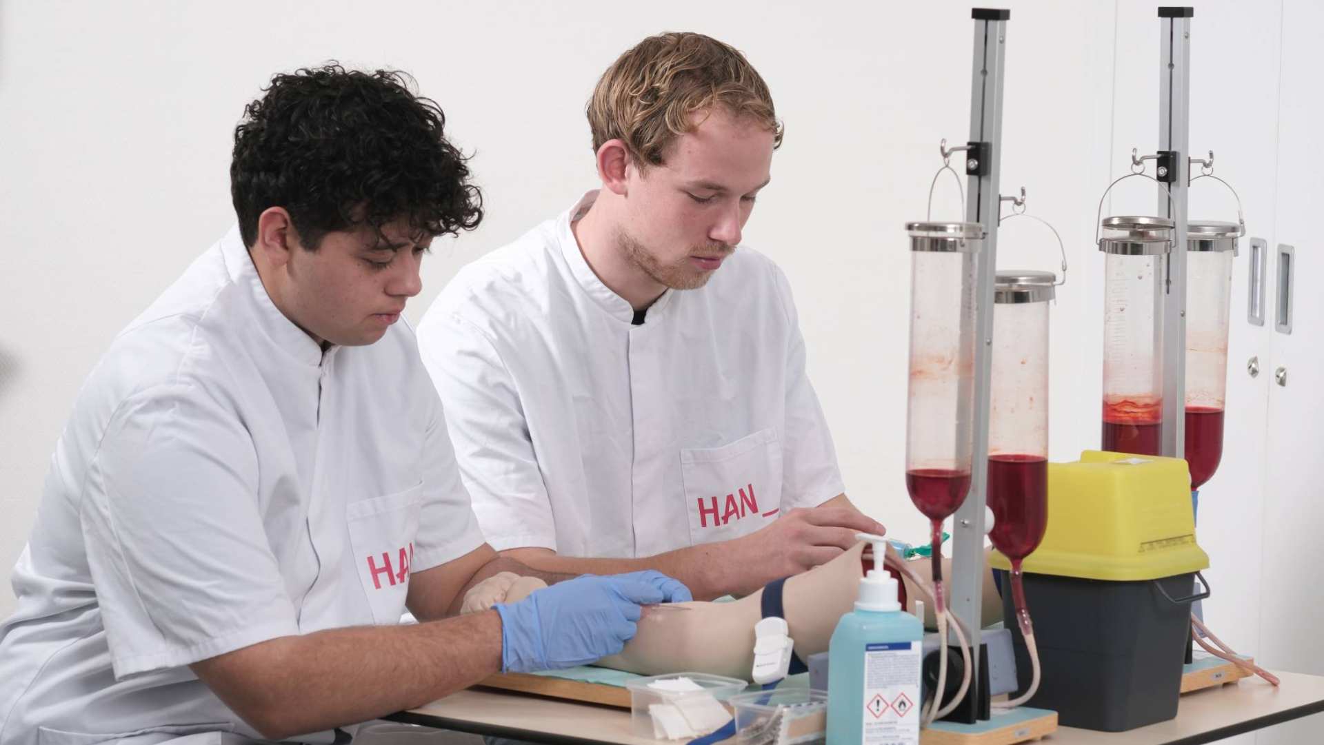 Studenten tijdens les bloesprikken oefenen op arm