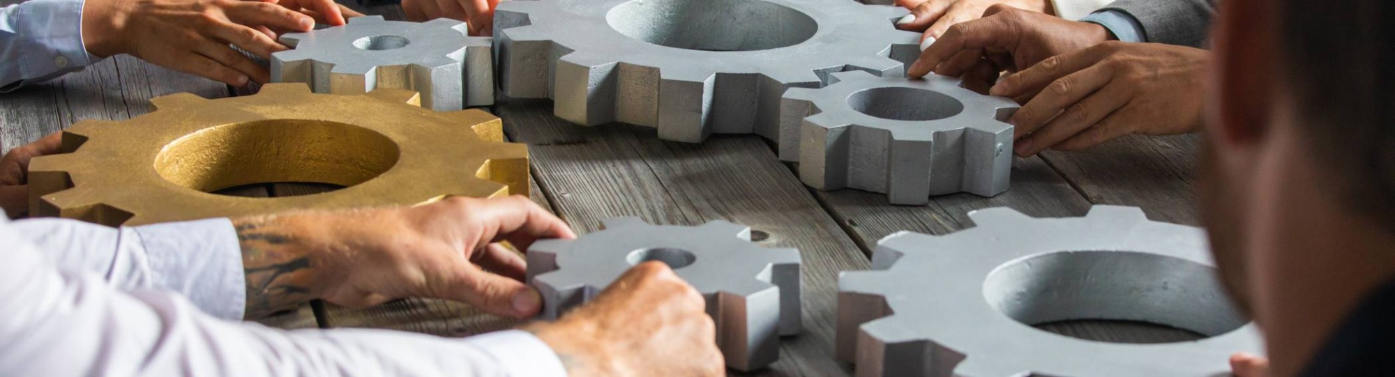 5 mensen aan een houten tafel draaien aan grote radars. Samenwerken. Seece