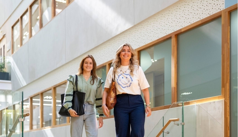 Twee studenten lopen door de gang van K35 en komen via de trap.