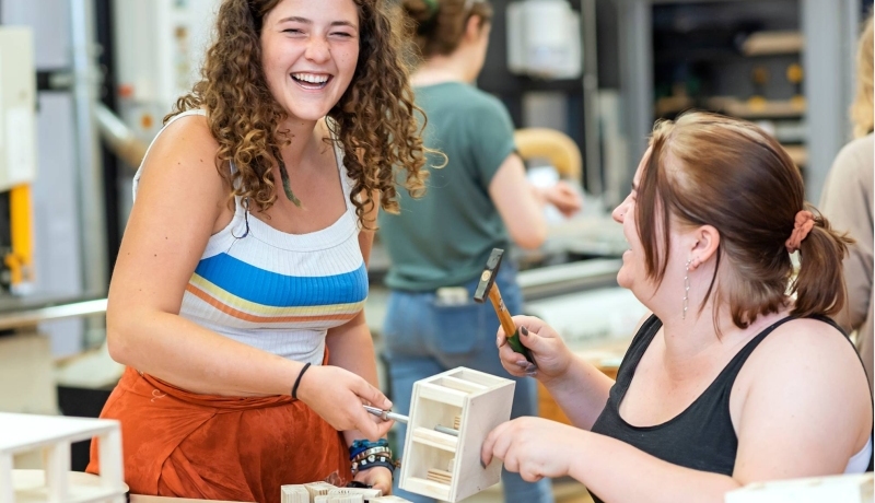 Twee beeldende therapie studenten werken samen aan een project in houtlokaal tijdens een praktijkles