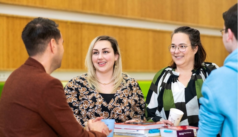 Twee vrouwen lachen tijdens een gesprek.