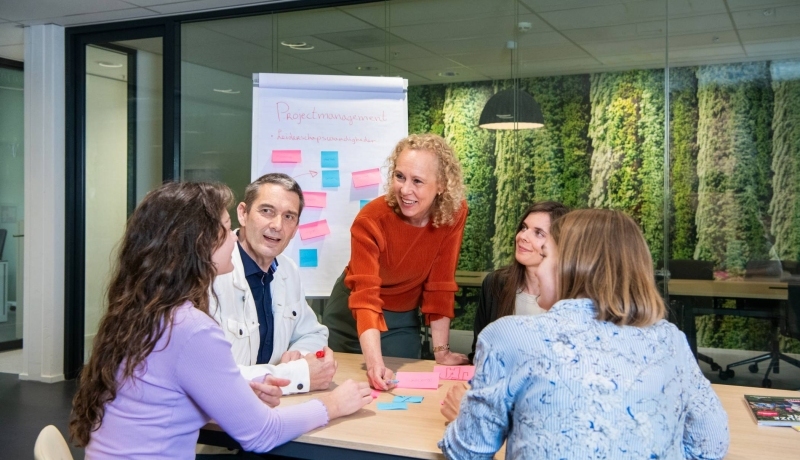 een deelnemer van Agile Scrum die een post it plakt op een flipover met meerdere gekleurde post its
