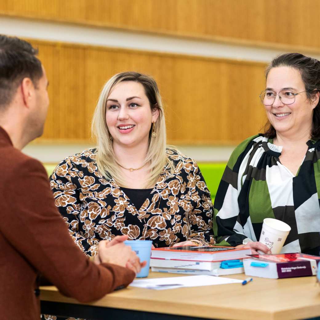 Twee vrouwen lachen tijdens een gesprek.