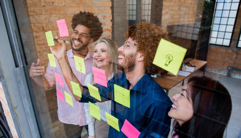 Groep jonge mensen plakken post-its op een glazen wand in een kantoor