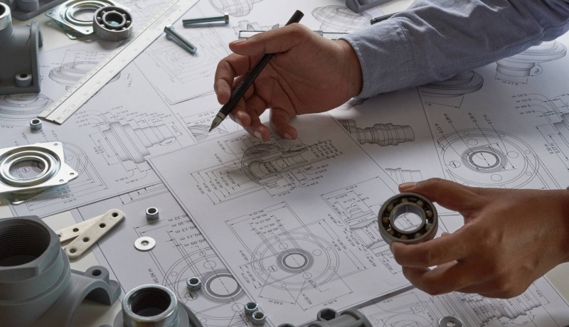 Engineer werkt aan ontwerp van mechanische onderdelen, zicht op blauwdruk