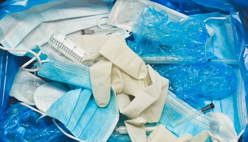 Op de foto staan zorgmiddelen, zoals blauwe mondkapjes, handschoenen, infiusen, spuiten en verpakkingsmateriaal, die gebruikt zijn. De vraag is of je altijd alle middelen moet gebruiken.