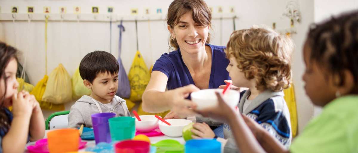 lerares met basisschool kinderen aan tafel tijdens de lunch