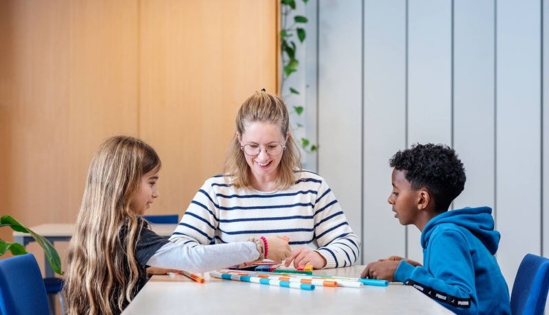 Juf met twee leerlingen aan een tafel