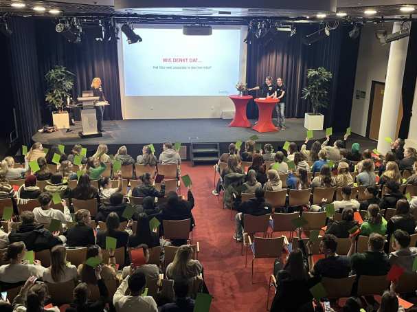 Foto's van de plenaire sessie met mbo-scholieren die groene kaartjes omhoog houden, voor de mbo-hbo proefstudeermiddag van Educatie en Mens en Maatschappij op 7 maart 2024