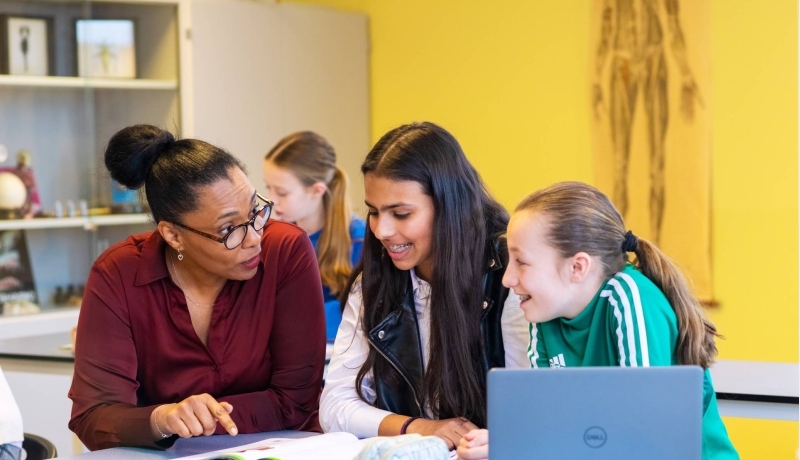 Eerstegraads docent legt iets uit aan 2 leerlingen.