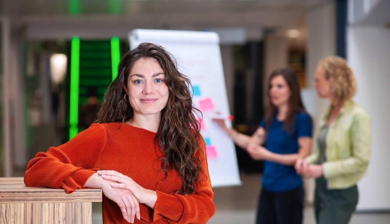 drie personen voor een bord met post-its aan het overleggen