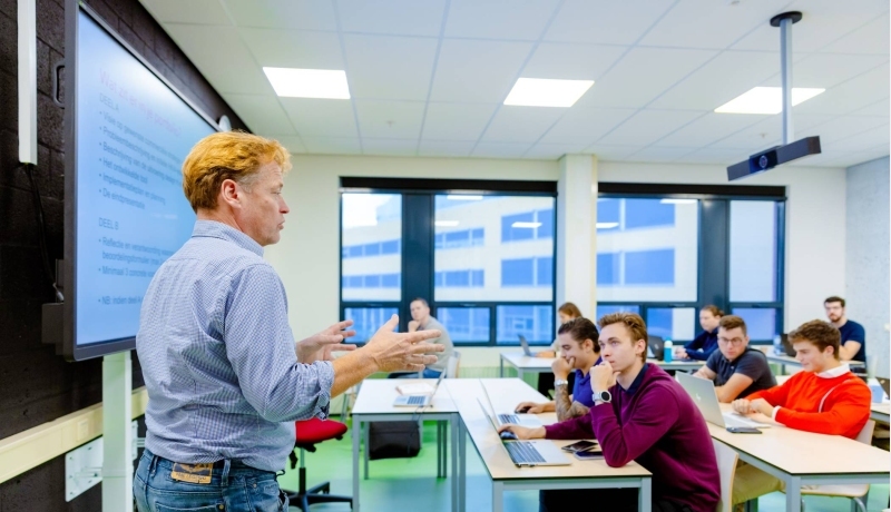 HAN duaal studenten Commerciële Economie luisteren naar docent die college geeft.