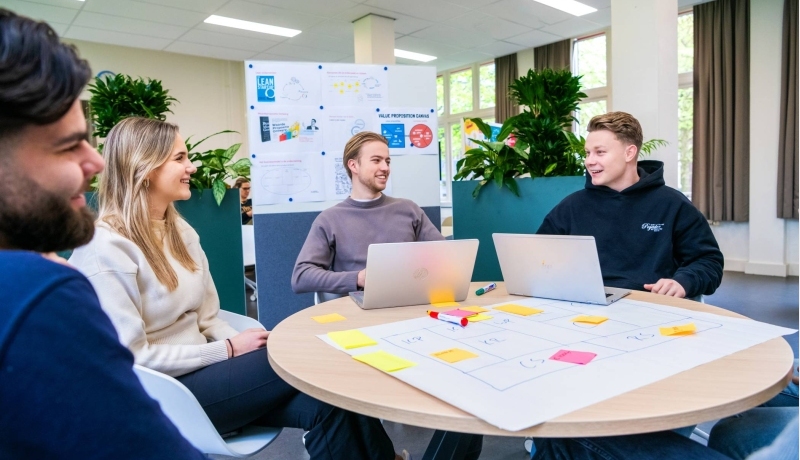 Een groep studenten aan tafel met laptops