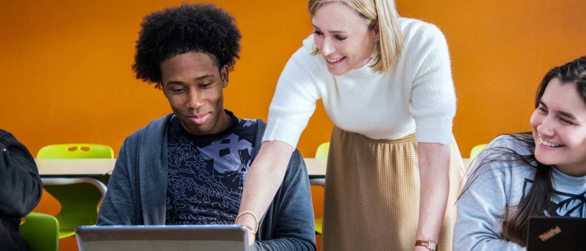 Foto Master Academie Educatie. Docent wijst op laptop scherm, terwijl 2 studenten kijken.