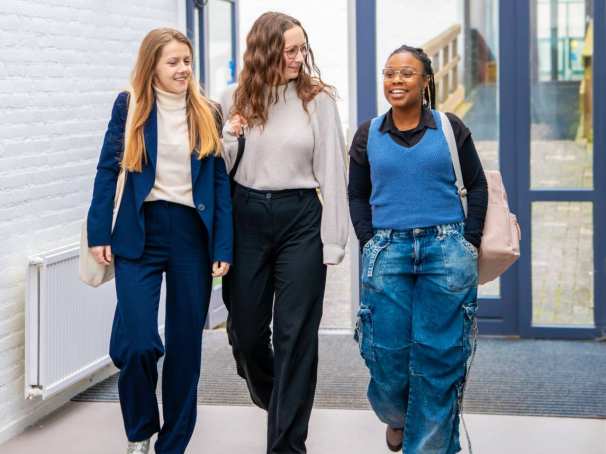 3 vrouwen lopen richting de camera, lachen met elkaar.