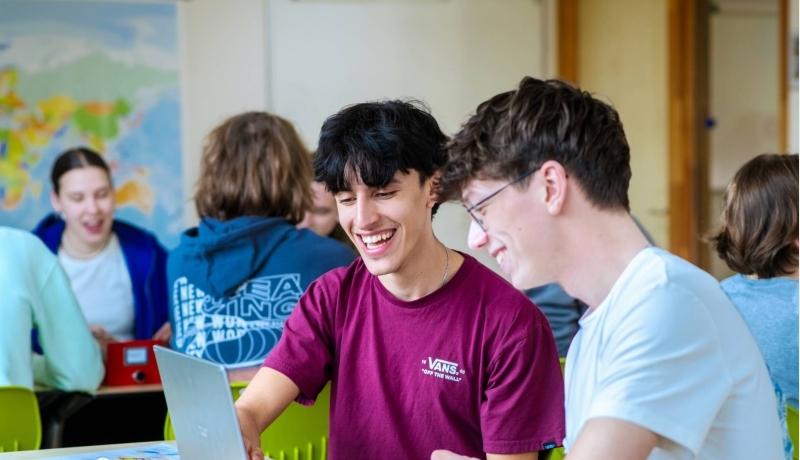 Drie studenten Leraar Frans krijgen uitleg van hun docent die tussen hen in staat.