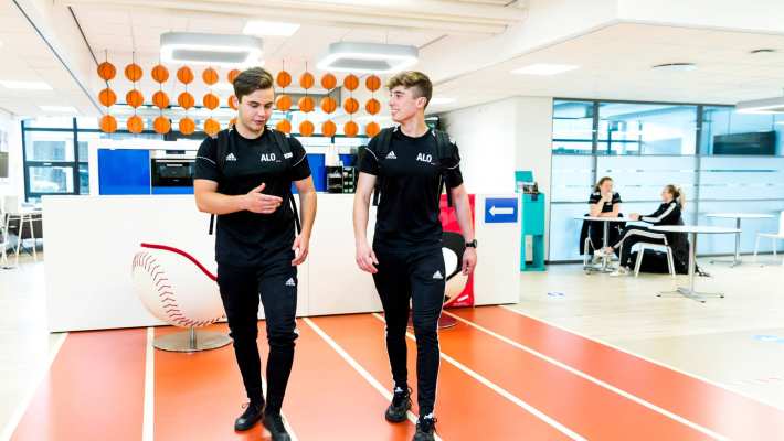 Twee jongens lopen in hun alo-tenue door de gang