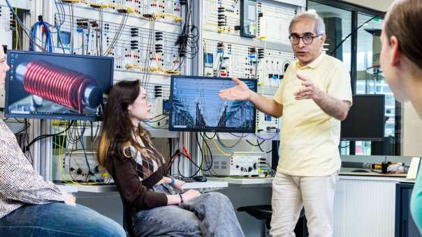 Studenten en docent elektrotechniek tijdens een les in het hoogspanningslab.