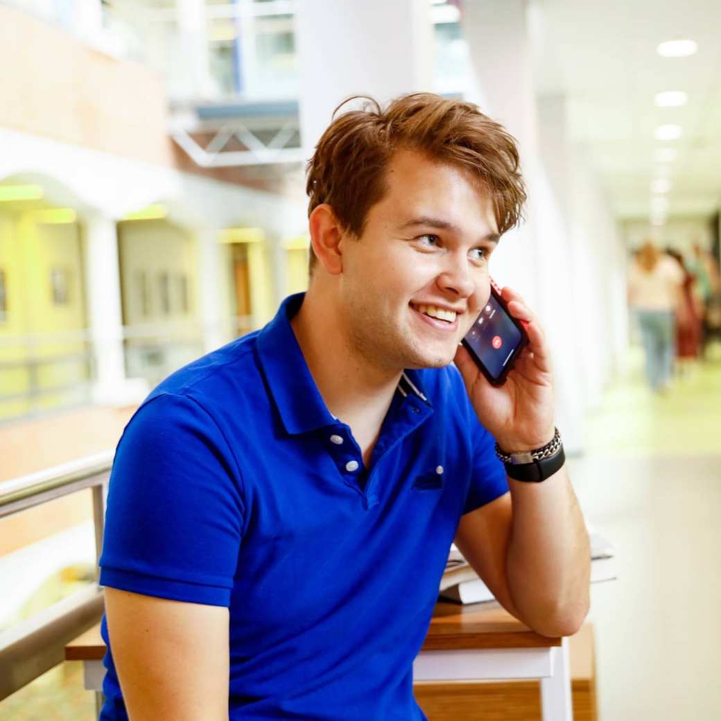 man bellen telefonisch overleg student hal gang