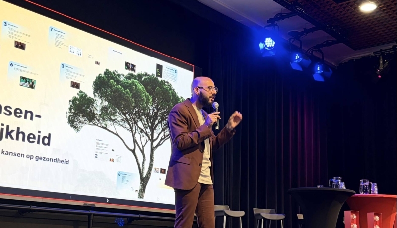Programmamaker Karim Amghar benadrukt het belang van kansenongelijkheid. Hij draagt een bruin pak en zwarte bril