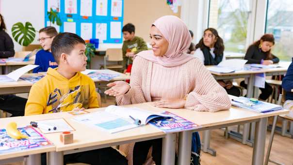 Juf uit traject Zij-instroom Leraar Basisonderwijs maakt vragend gebaar naar haar leerlingen.