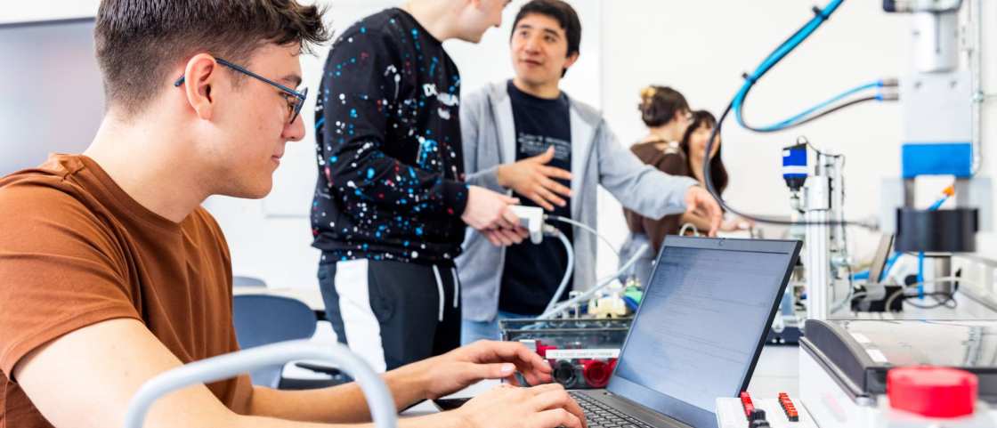 Een elektrotechniekstudent werkt op de laptop tijdens practicum.